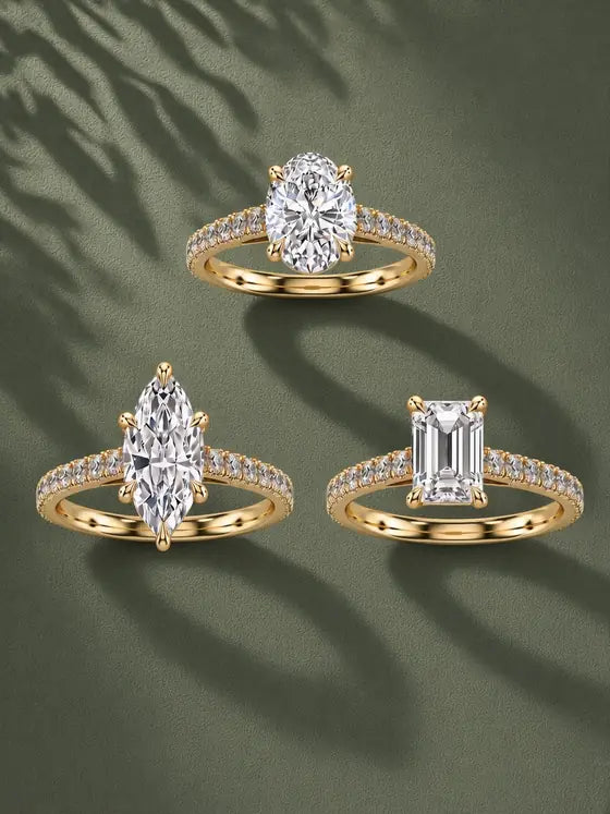 Three solitaire engagement rings with diamond-set scalloped yellow gold bands in oval, marquise and emerald cuts